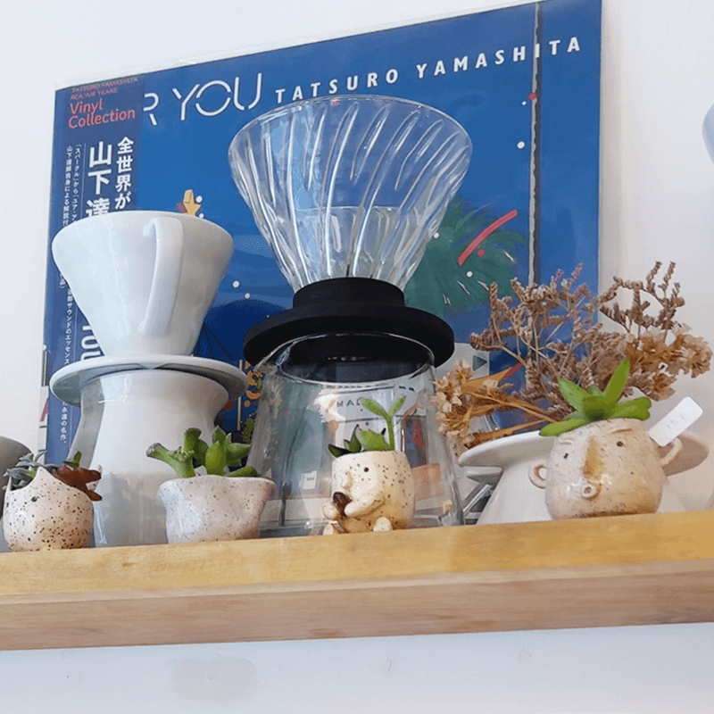 Miniature ceramic planters on a shelf beside coffee brewing equipment at Background coffee, Paris