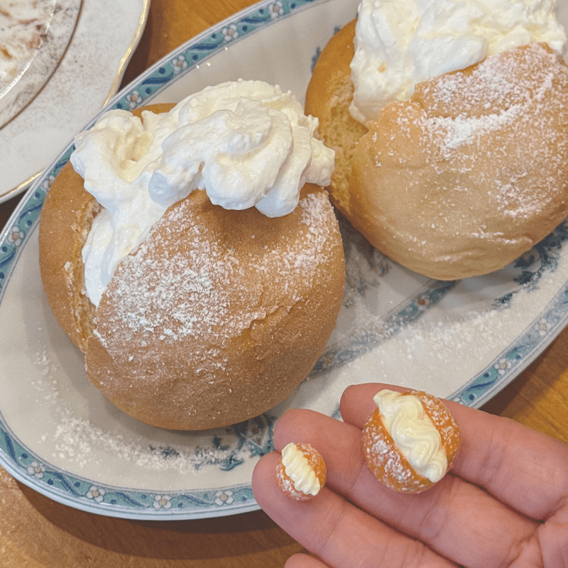 Miniature cream-topped pastry earrings displayed beside a real pastry at Nanù, Paris
