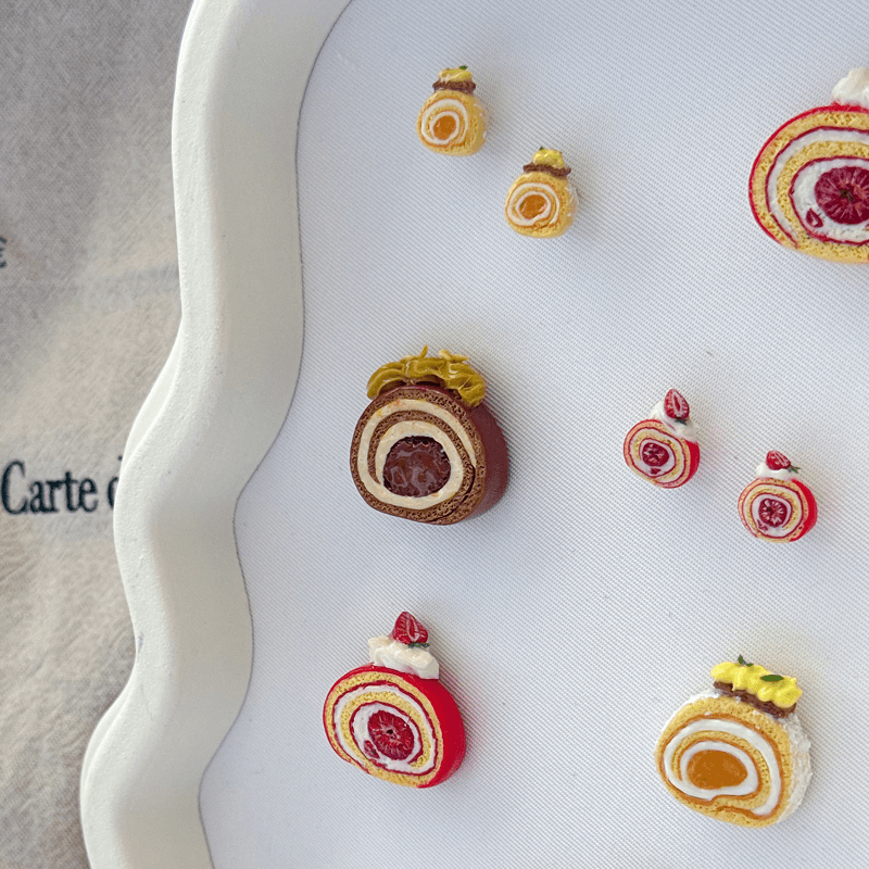 Miniature roll-cake earrings displayed on a tray at Chāo Pâtisserie, Paris