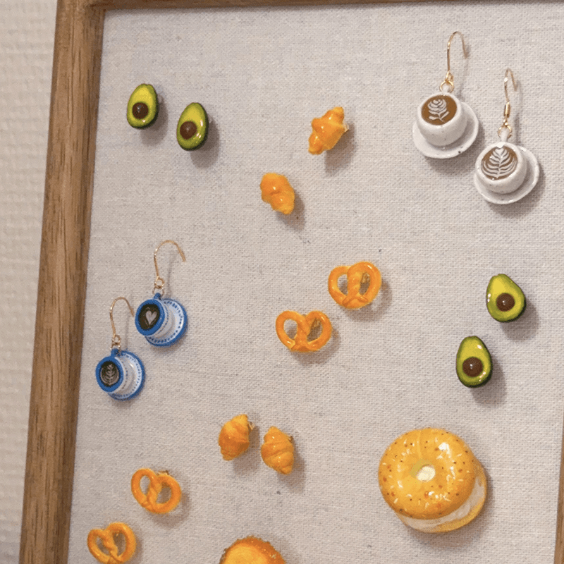 Miniature bakery-inspired earrings displayed on linen at TÊTE-À-TÊTE Cafeteria, New York